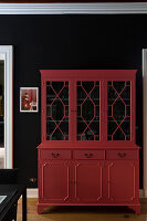 Red display cabinet in front of black wall