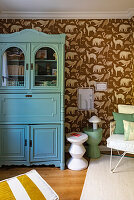 Children's room with mint blue display cabinet, wallpaper with animal motifs and sculptural side tables