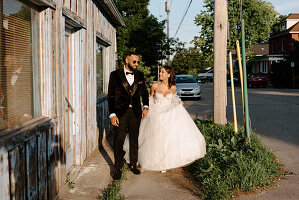 Bride and groom walking on sidewalk in town