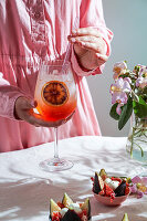 Aperol Spritz cocktail, on pale pink linen tablecloth, shade, sunlight, summer drink in a glass