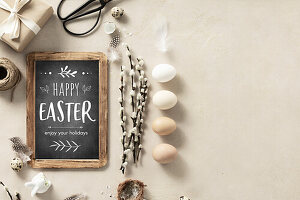 Easter composition with vintage Easter decorations and Happy Easter chalk board on beige stone background top view flat lay copy space