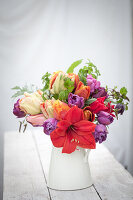 Blumenarrangement mit roter Amaryllis (Hippeastrum) und bunten Tulpen (Tulipa) in Krug