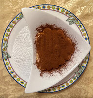 Tiramisu auf dreieckigem Teller mit Kakaopulver bestäubt