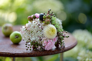 Spätsommerstrauß mit Rosen, Dahlien (Dahlia) und Beeren auf Gartentisch