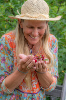 Woman harvesting cherries (Prunus Avium) and holding fruit in her hands, portrait