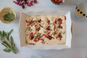 Unbaked focaccia with sun-dried tomatoes and herbs