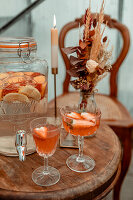 Rustic wooden table with aperitif glasses and decorative flower arrangement