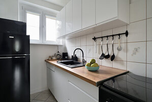 Bright kitchen with wooden worktop, black hob and black fridge