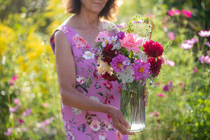 Frau mit Blumenstrauß aus Dahlien (Dahlia), Rosen (Rosa), Herbstanemonen (Anemone Hupehensis) und wilde Möhre