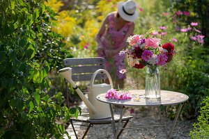 Gartensitzplatz mit Blumenstrauß aus Dahlien (Dahlia), Rosen (Rosa), Herbstanemonen (Anemone Hupehensis) und wilde Möhre