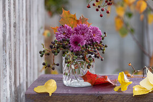 Strauß aus Chrysanthemen (Chrysanthemum), Wildem Wein mit Hagebutten in Glasvase