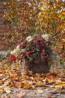 Gesteck im Herbst aus Waldrebe, Fetthenne, Hagebutten, Eukalyptus, Wildem Wein in Weidenkorb