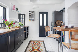 Kitchen with black cabinets, wooden counter and patterned carpet runner