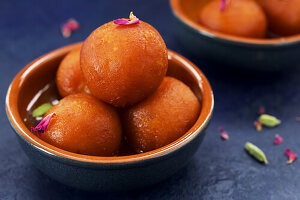 A bowl of gulab jamun on blue background