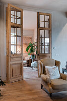 Spacious living area with double doors and wooden floor, armchair in the foreground