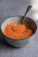 Raw red lentil beans in the bowl on the concrete background of kitchen table