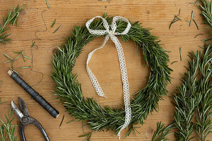 Rosemary wreath with lace and winding wire on a wooden table