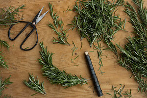 DIY-Rosmarinkranz (Rosmarinus officinalis) mit Wickeldraht auf Holztisch