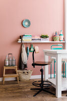 Living area with pink wall and wooden floor, decorated with colourful accessories