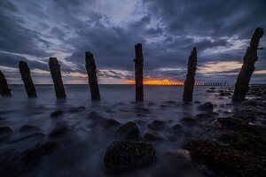 Sturmwolken sammeln sich über der Irischen See, verschlissene Seeverteidigungsanlagen von South Walney bei Sonnenuntergang von der Cumbrian Coast, Cumbria, England, Vereinigtes Königreich, Europa