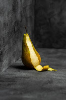 Pear against a grey background, partially peeled