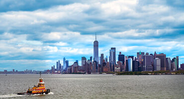 Tugboat crossing New York Bay with lower Manhattan skyline in background, New York City, New York, USA