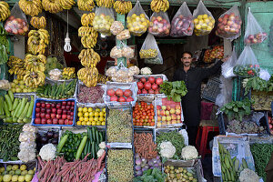 Pakistan, Gilgit, ein Mann posiert in seinem bunten Gemüse- und Obstladen