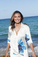 Frau in weißer Bluse mit blauem Blumenmuster am Strand