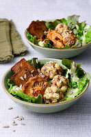 Laugenknödel-Bowl mit Salat, veganem Speck und Sonnenblumenkernen