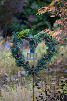 Heart made of various fir greenery with lantern in the garden