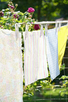 Bunte Wachstücher auf Wäscheleine im sonnigen Garten