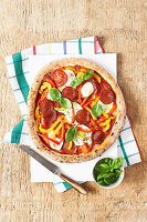 Pepperoni pizza with peppers, mozzarella and basil