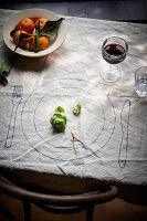 Drawing of a place setting with red wine and clementines