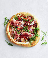 Pizza mit Prosciutto, Rucola, Zwiebeln und Oliven