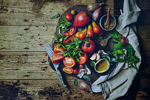 Assorted tomatoes and fresh herbs on a wooden board