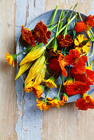 Edible flowers on a plate: marigold, nasturtium, courgette flowers, marigolds