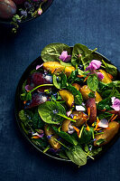 Spinach salad with plums, mint and edible flowers