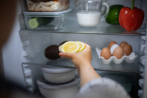 Woman puts lemon slices in the fridge