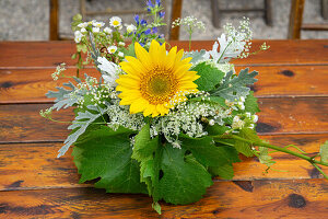 Tischschmuck mit Wildblumen, Sonnenblume und Weinblättern