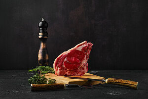 Raw beef chop with fresh herbs and pepper mill