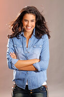 Young woman in denim shirt and trousers, crossed arms