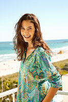 Young woman in patterned tunic on the beach, standing