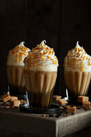 Three fresh caramel lattes, with cream topping, salted caramel sauce and toffee pieces