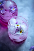 Frühlingscocktail mit Eis und Stiefmütterchenblüten