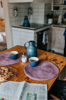 Thermos and coffee in cups on wooden table in kitchen