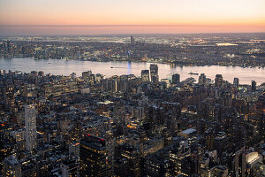 Aerial view of illuminated buildings in city against sky during sunset