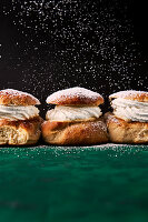 Semla-Brötchen mit Sahne und Puderzucker auf einer grünen Unterlage