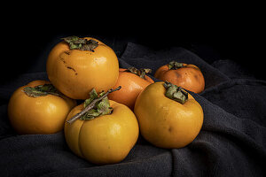 Frische Kaki (Diospyros kaki) auf dunklem Tuch