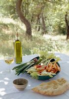 Gemüse, Weißbrot, Olivenöl und Weinglas auf Tisch im Freien