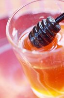 Pot of honey and wooden honey spoon